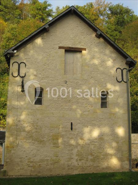 Façade en pierre d'un bâtiment ancien avec deux petites fenêtres, une porte en hauteur et un décor métallique.