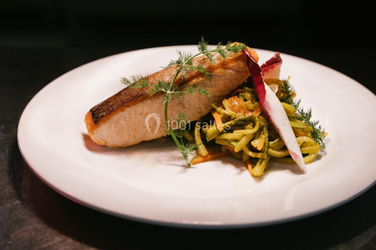 Filet de saumon grillé servi avec des légumes croquants et des herbes fraîches sur une assiette blanche.