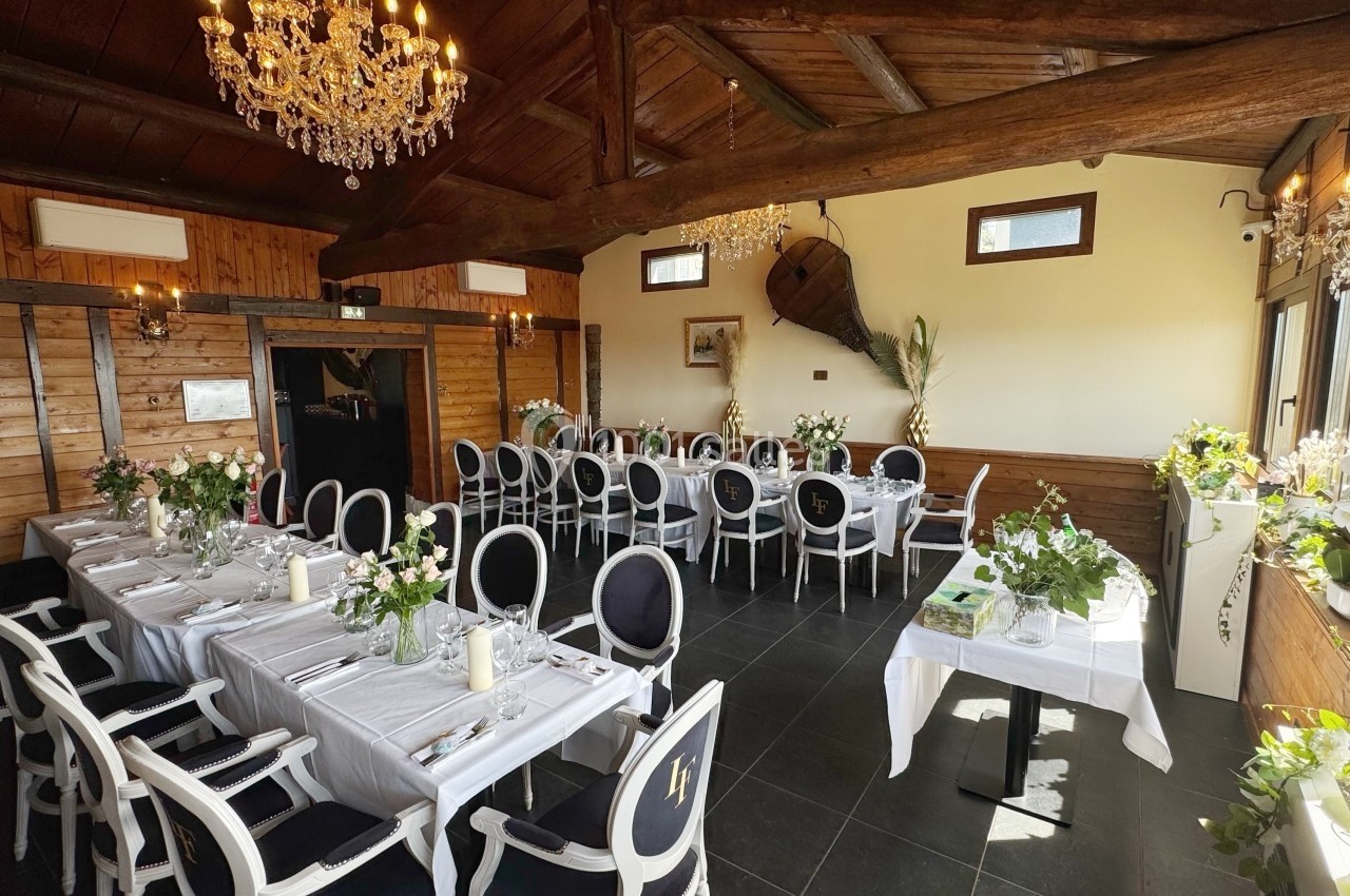 Salle de réception lumineuse avec tables dressées, chaises élégantes, décorations florales et lustres en cristal.