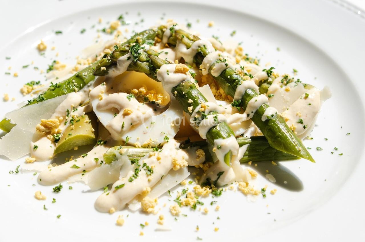 Assiette de légumes verts et blancs garnis de sauce crémeuse et d'herbes fraîches, servie sur une table lumineuse.