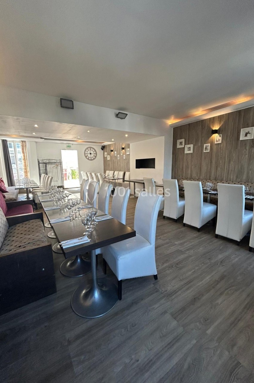 Salle de restaurant lumineuse avec tables dressées, chaises blanches et banquettes, décor moderne et épuré.