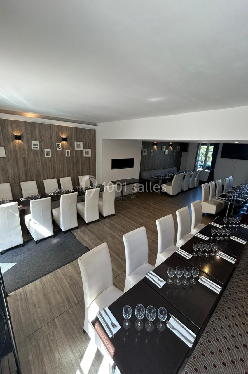 Salle de restaurant lumineuse avec tables dressées, chaises blanches et décoration murale sobre.