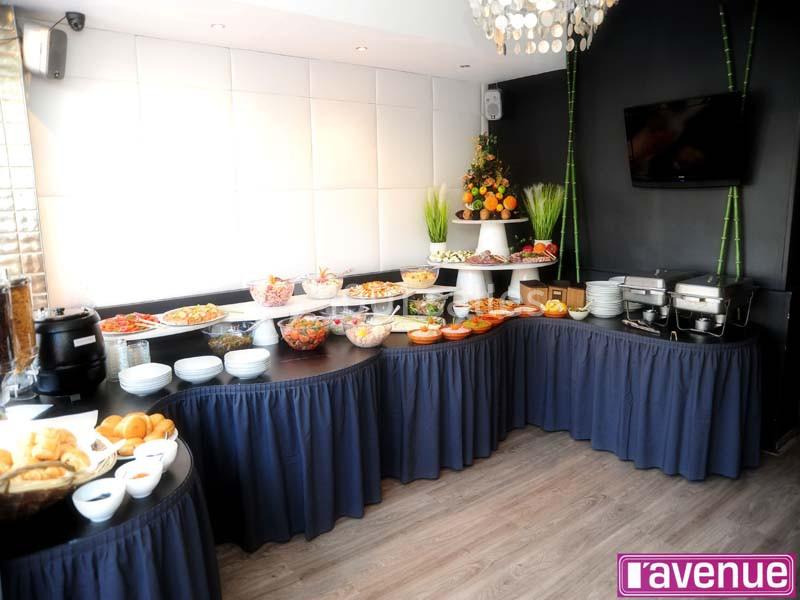 Buffet varié avec plats chauds, froids et desserts, présenté sur des tables drapées dans une salle lumineuse.