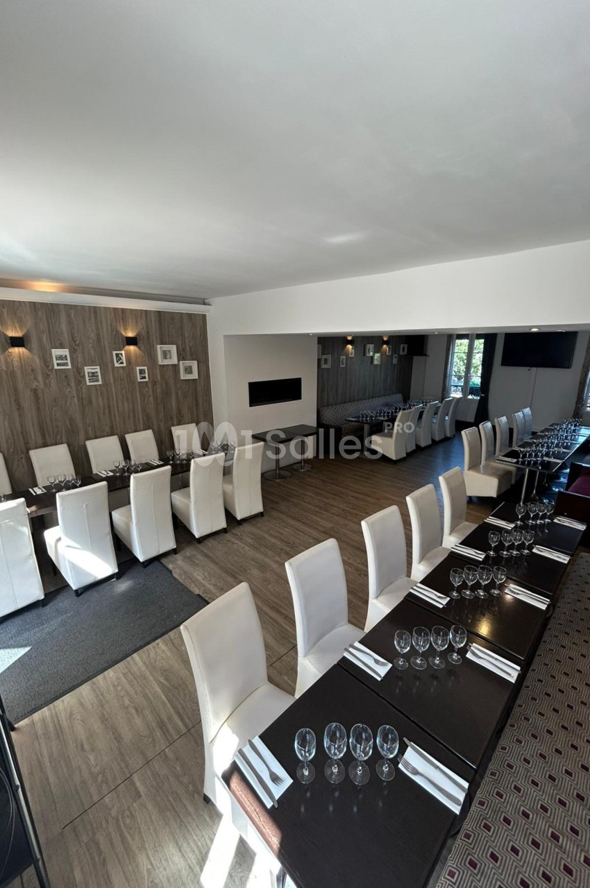 Salle de restaurant lumineuse avec tables dressées, chaises blanches et décoration murale sobre.
