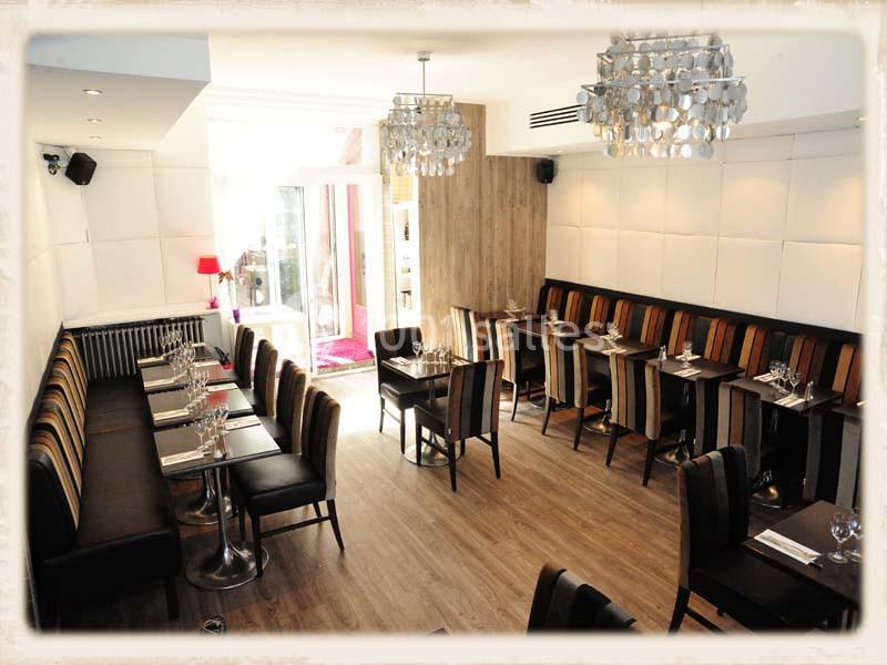 Salle de restaurant lumineuse avec tables alignées, chaises rembourrées et décor moderne aux tons neutres.