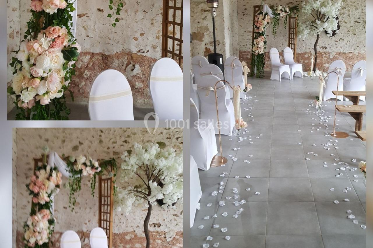 Salle de cérémonie décorée avec des chaises blanches, des arches fleuries et des pétales de fleurs au sol.