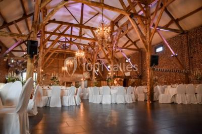 Un couple en tenue de mariage se tient la main dans un jardin baigné par une lumière douce au coucher du soleil.