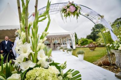 Un couple en tenue de mariage se tient la main dans un jardin baigné par une lumière douce au coucher du soleil.