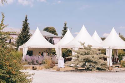 Un couple en tenue de mariage se tient la main dans un jardin baigné par une lumière douce au coucher du soleil.