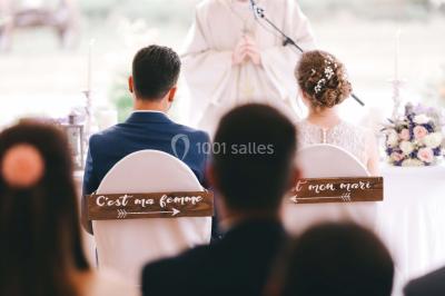 Un couple en tenue de mariage se tient la main dans un jardin baigné par une lumière douce au coucher du soleil.