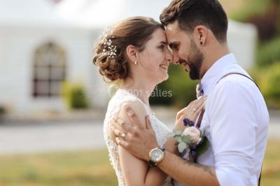 Un couple en tenue de mariage se tient la main dans un jardin baigné par une lumière douce au coucher du soleil.