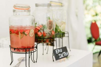 Un couple en tenue de mariage se tient la main dans un jardin baigné par une lumière douce au coucher du soleil.