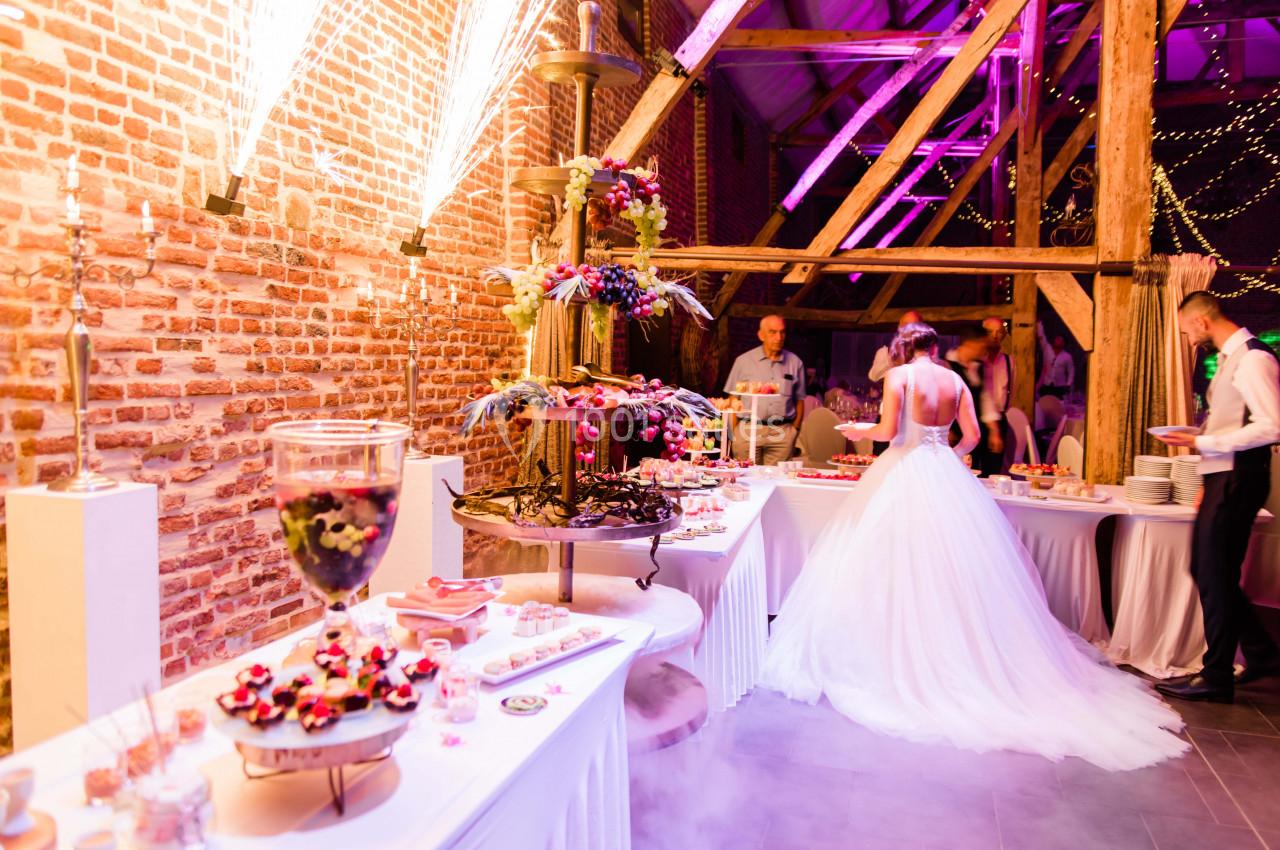 Buffet de desserts décoré avec une fontaine de chocolat dans une salle de réception éclairée par des lumières colorées.