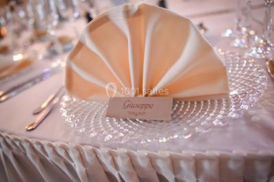 Un couple en tenue de mariage se tient la main dans un jardin baigné par une lumière douce au coucher du soleil.