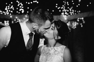 Un couple en tenue de mariage se tient la main dans un jardin baigné par une lumière douce au coucher du soleil.