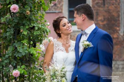 Un couple en tenue de mariage se tient la main dans un jardin baigné par une lumière douce au coucher du soleil.