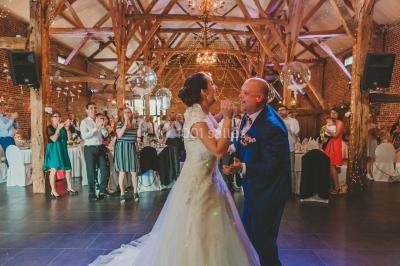 Un couple en tenue de mariage se tient la main dans un jardin baigné par une lumière douce au coucher du soleil.