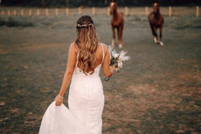 Un couple en tenue de mariage se tient la main dans un jardin baigné par une lumière douce au coucher du soleil.