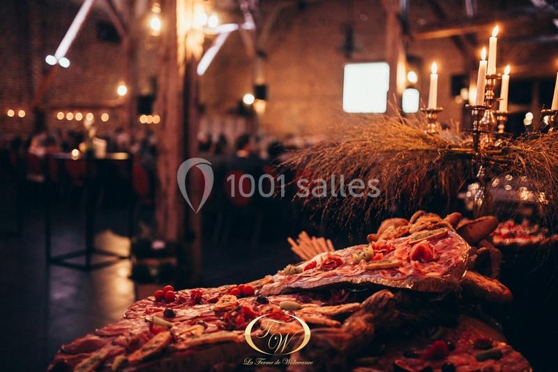 Plateau de charcuterie et pains disposé dans une salle de réception éclairée par des bougies.