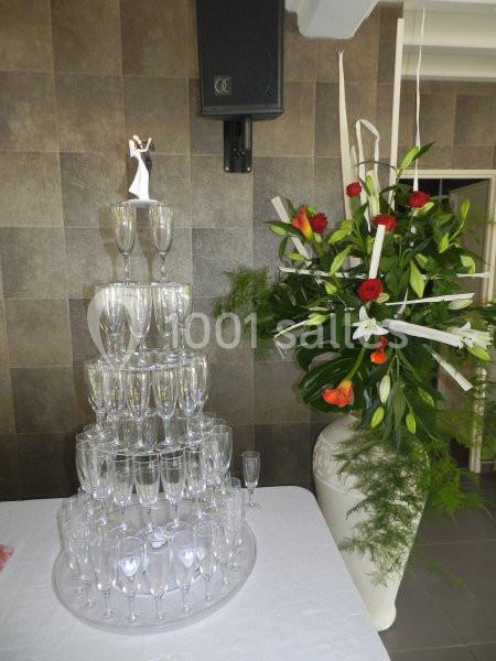 Pyramide de flûtes à champagne avec une figurine de mariage au sommet, à côté d'un grand bouquet floral.