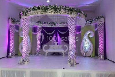 Miniature Location salle Montmorency (Val-d'Oise) - Le Concept Réception #9 Mains d'un couple portant des alliances, posées sur un bouquet de fleurs blanches et violettes.