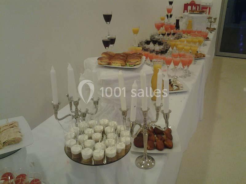 Buffet avec verrines, chandeliers, mini-sandwichs, jus de fruits et pâtisseries disposés sur une table blanche.