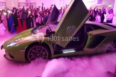 Miniature Location salle Saint-Germain-lès-Arpajon (Essonne) - Voilier 91 #8 Voiture de sport verte aux portes papillon ouvertes, entourée de fumée et d'une foule dans un lieu éclairé.