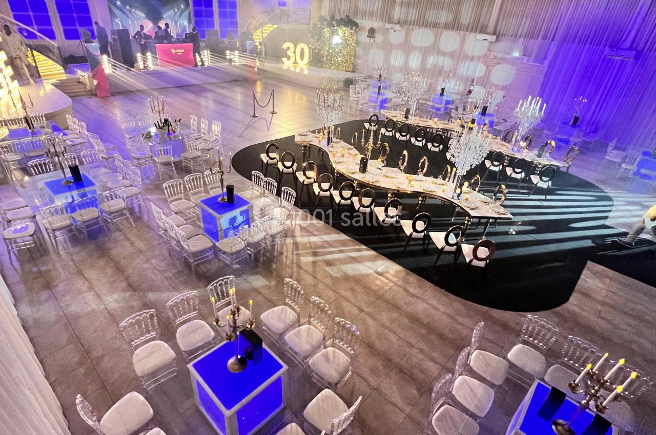 Location salle Saint-Germain-lès-Arpajon (Essonne) - Voilier 91 #6 Salle de réception décorée avec des tables, chaises transparentes et éclairages bleus et blancs pour un événement.
