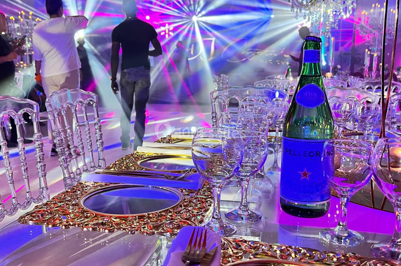 Location salle Saint-Germain-lès-Arpajon (Essonne) - Voilier 91 #7 Table élégamment dressée avec des assiettes dorées, vue sur une piste de danse illuminée par des jeux de lumière colorés.