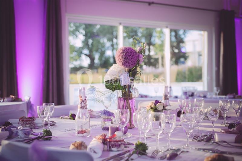 Table décorée pour un événement avec vaisselle élégante, centre de table floral et éclairage d'ambiance violet.