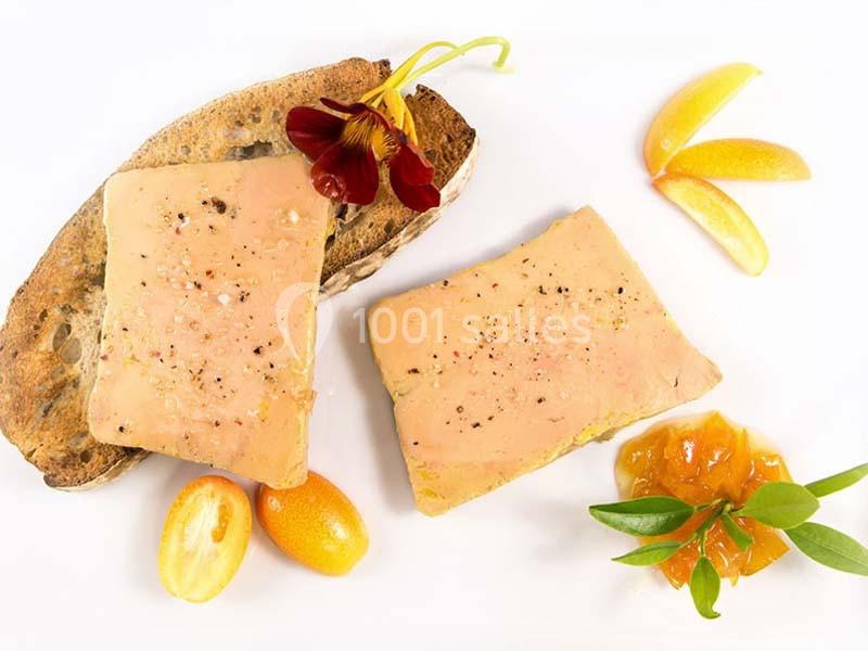 Tranches de foie gras sur pain grillé, accompagnées de confiture, kumquats et décoration florale.