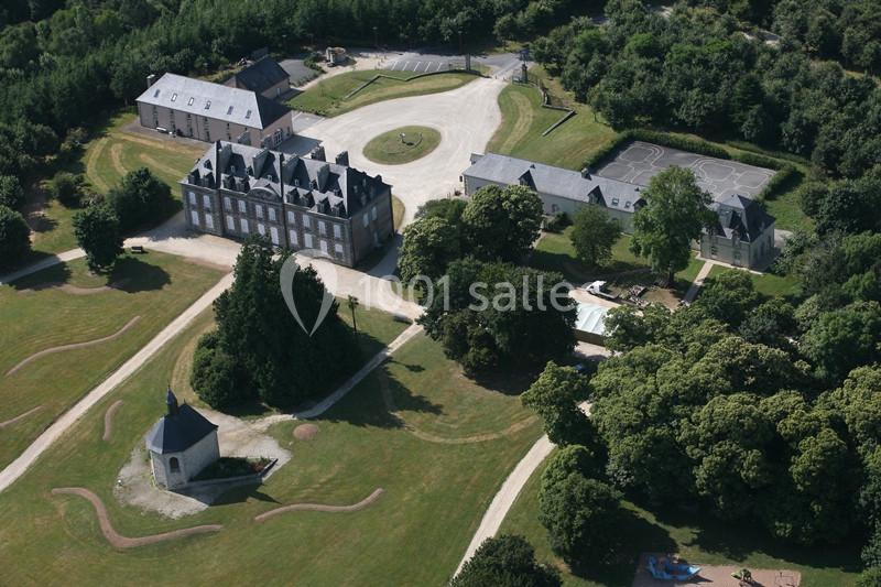 Vue aérienne d'un domaine avec un château, une chapelle, des bâtiments annexes, des terrains de sport et des espaces verts.