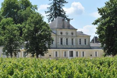 Inscription ’NOUCHET’ gravée sur une façade en pierre et briques, entourée de végétation en arrière-plan.