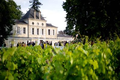 Inscription ’NOUCHET’ gravée sur une façade en pierre et briques, entourée de végétation en arrière-plan.