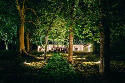 Inscription ’NOUCHET’ gravée sur une façade en pierre et briques, entourée de végétation en arrière-plan.