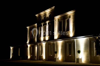 Inscription ’NOUCHET’ gravée sur une façade en pierre et briques, entourée de végétation en arrière-plan.