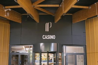 Miniature Entrée Casino Menu posé sur une table ronde dans un bar élégant avec un comptoir éclairé en arrière-plan.