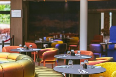 Miniature Restaurant Menu posé sur une table ronde dans un bar élégant avec un comptoir éclairé en arrière-plan.