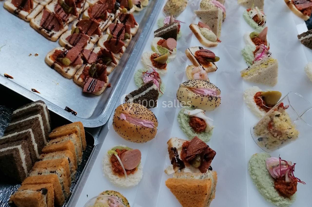 Location salle Crosne (Essonne) - Aux Tulipes #5 Plateaux de bouchées apéritives variées disposées en rangées sur une table, prêtes pour un service traiteur.
