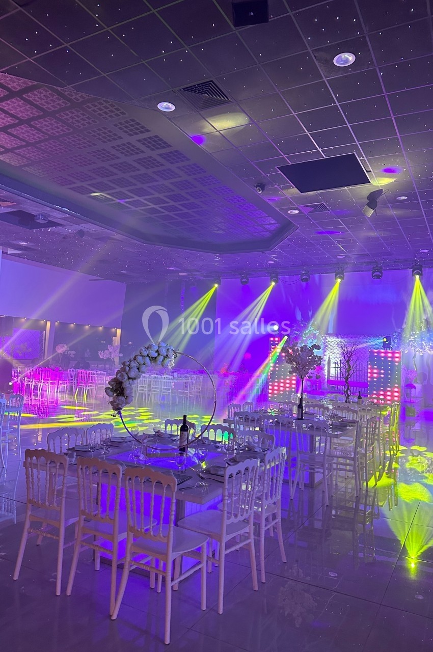 Location salle Crosne (Essonne) - Aux Tulipes #2 Salle de réception décorée avec des tables et des chaises, éclairée par des lumières colorées et des projecteurs.