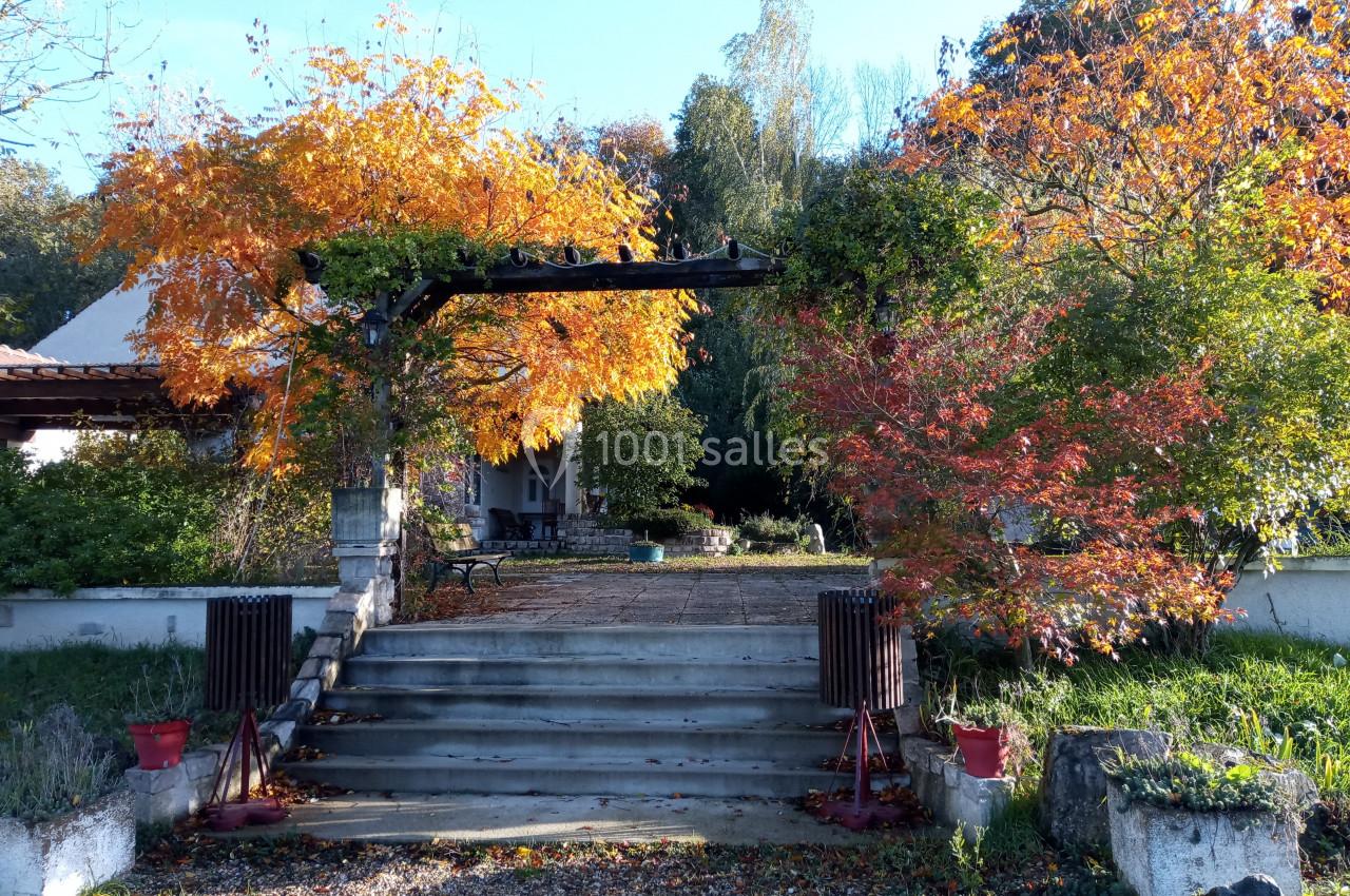 Escalier en pierre menant à une terrasse entourée d'arbres aux feuilles d'automne rouges et orange.