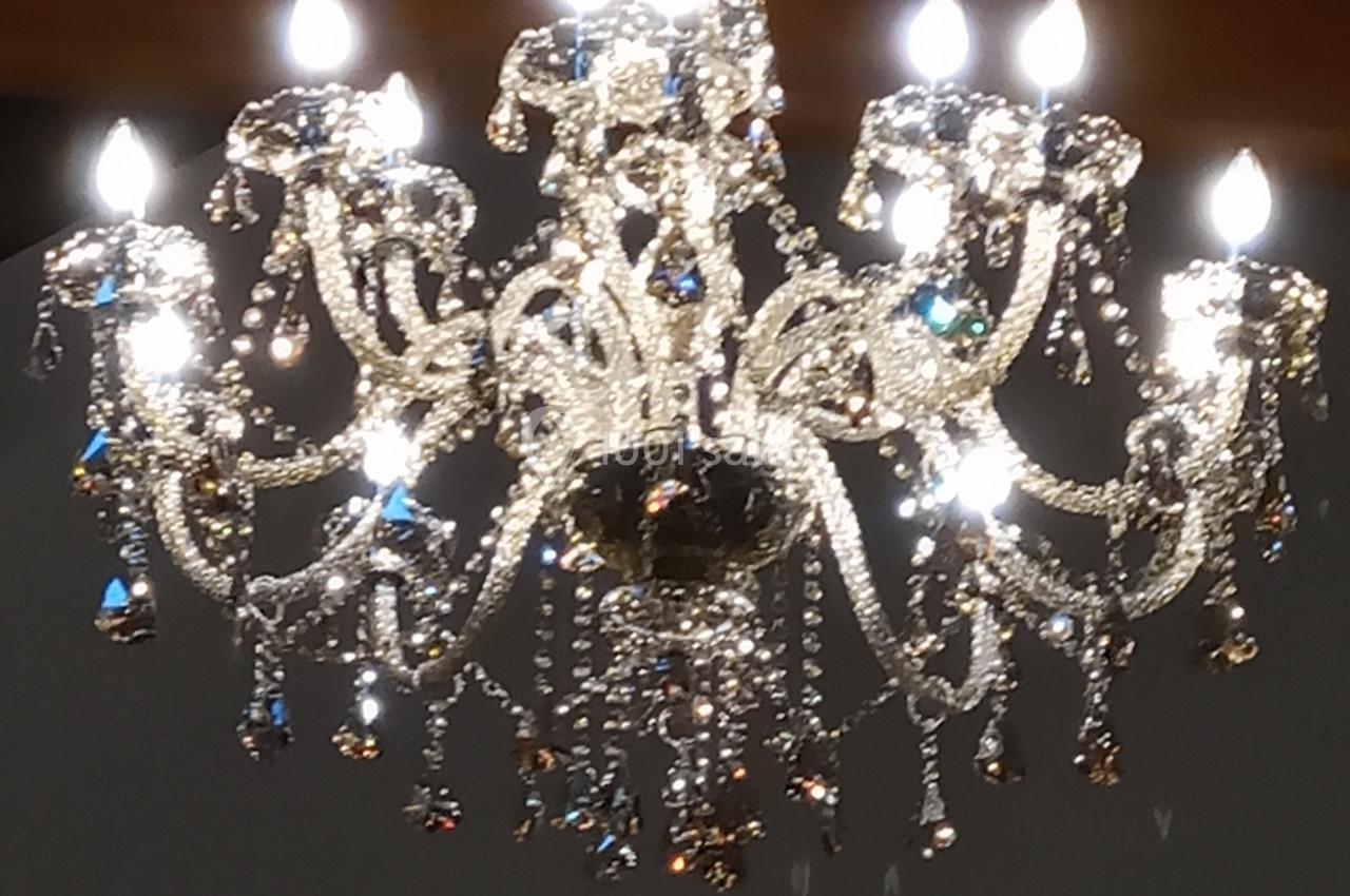 Lustre en cristal suspendu, éclairé avec des ampoules, reflétant la lumière dans un intérieur sombre.