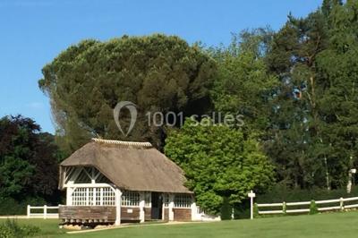 Pont éclairé et kiosque en bois près d'une fontaine illuminée, entourés d'arbres dans un parc nocturne.