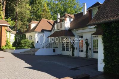 Pont éclairé et kiosque en bois près d'une fontaine illuminée, entourés d'arbres dans un parc nocturne.