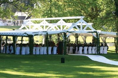 Pont éclairé et kiosque en bois près d'une fontaine illuminée, entourés d'arbres dans un parc nocturne.