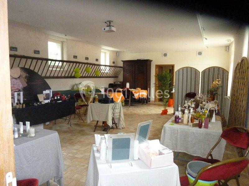 Salle aménagée avec des tables présentant des produits cosmétiques et des chaises disposées autour.