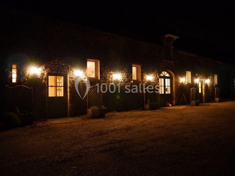 Façade d'un bâtiment en pierre éclairée par des lampes extérieures dans l'obscurité de la nuit.