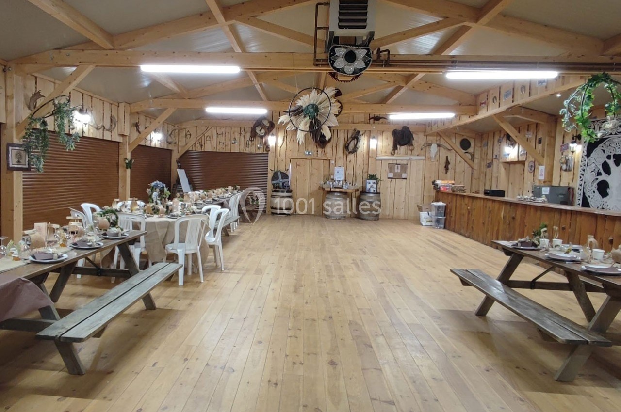 Salle en bois décorée dans un style rustique, avec tables dressées pour un repas et éléments de décoration champêtre.