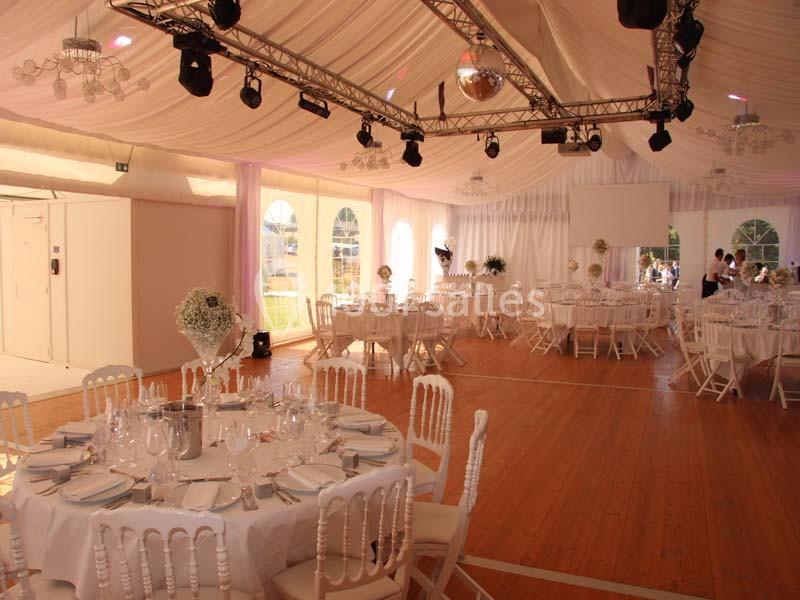 Location salle Meyrignac-l'Église (Corrèze) - Domaine des Monédières #1 Salle de réception décorée avec des tables rondes dressées, chaises blanches et plafond drapé de tissu clair.