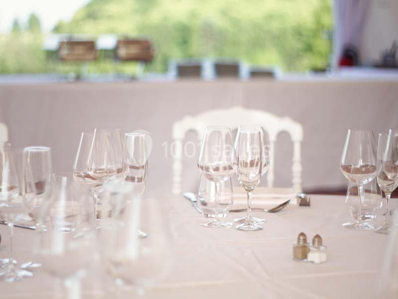 Location salle Meyrignac-l'Église (Corrèze) - Domaine des Monédières #14 Table élégamment dressée avec des verres à vin, couverts et nappes blanches, en arrière-plan flou.